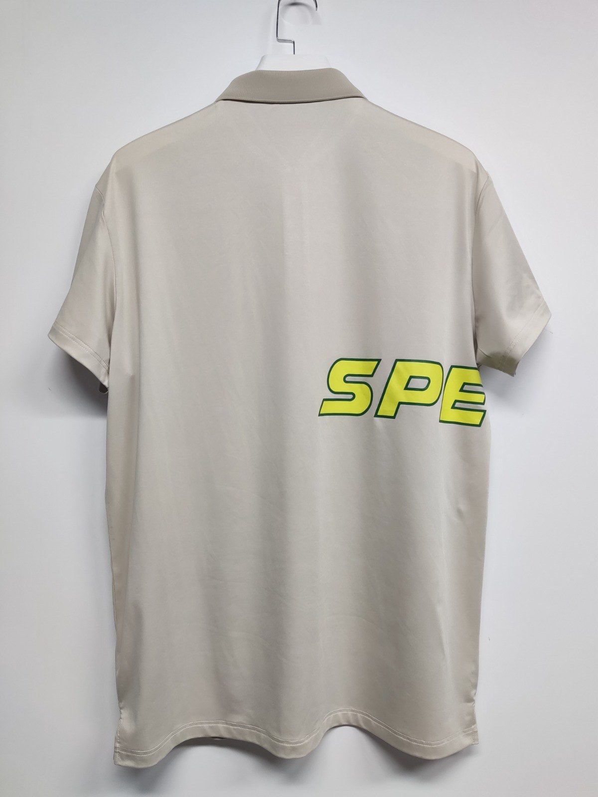Back view of the cream SPEEDY polo showing the wraparound SPEEDY logo